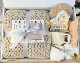 Caja de regalo navideña Hygge con manta, lámpara de madera en forma de casita y tetera.