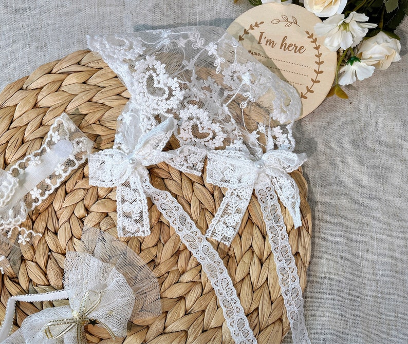 May include: White lace trim with bows and a sign that says "I'm here".