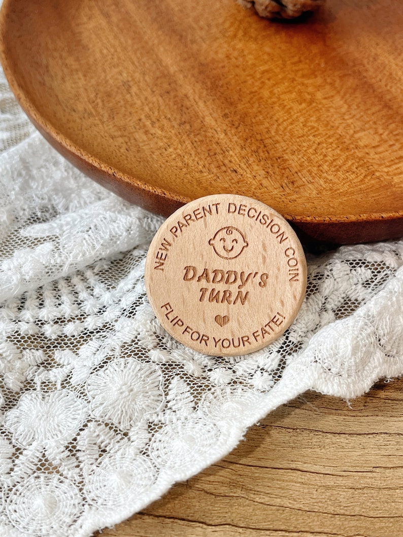 May include: A wooden coin with the text "New Parent Decision Coin" and "Daddy's Turn" with a heart symbol. The coin also says "Flip for your fate!"