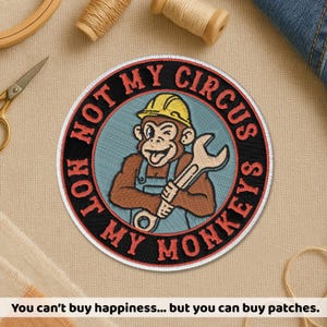 May include: Circular embroidered patch featuring a monkey in a yellow hard hat holding a wrench. The patch reads "NOT MY CIRCUS, NOT MY MONKEYS" in a circular design. The patch is black, red, brown, and blue.
