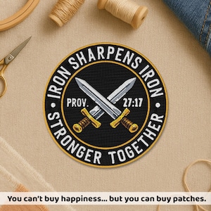 May include: Round black patch with gold and white text and crossed swords. The patch reads "IRON SHARPENS IRON STRONGER TOGETHER" with "PROV. 27:17" in the center. The patch has a gold border and is on a tan fabric.