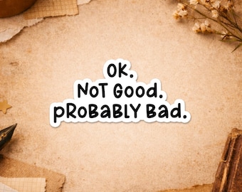 May include: A white sticker with the text "Ok. NOT Good. PROBABLY Bad." is displayed on a textured background. The sticker is surrounded by torn paper and dried flowers. The text "Happiness comes in small sticky pieces" is at the bottom.