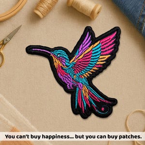 May include: A colorful hummingbird patch with a black border. The bird features vibrant shades of pink, purple, blue, and yellow. The text at the bottom reads: "You can't buy happiness... but you can buy patches."