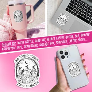 May include: Black and white sticker with the text "GOD FORBID WOMEN HAVE HOBBIES" and an illustration of witches dancing in a circle. The sticker is shown on a pink tumbler, a laptop, and a phone.