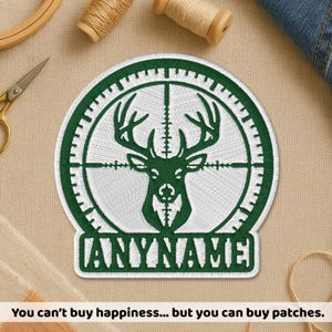 May include: Embroidered patch with a green deer head inside a scope design, and the text "ANYNAME" below. The patch is white with green detailing. The text at the bottom reads: "You can't buy happiness... but you can buy patches."