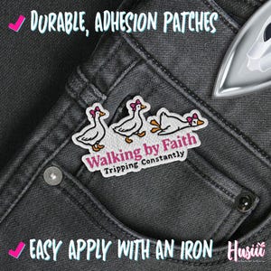 May include: Embroidered patch with three cartoon geese wearing pink bows, the text "Walking by Faith, Tripping Constantly" on grey denim. The patch is designed for iron-on application.