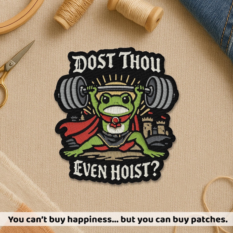 Puede incluir: Parche bordado con una rana verde levantando pesas, con capa y un peque&ntilde;o castillo. El texto "DOST THOU EVEN HOIST?" est&aacute; arriba y abajo de la rana. Sobre un fondo de tela beige.
