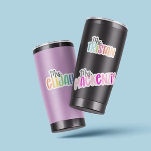K&ouml;nnte beinhalten: Zwei Edelstahlbecher mit bunten Vinyl-Aufklebern. Die Aufkleber sagen "Mrs. Tristan" und "Mrs. Mackenzie".