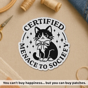 May include: Embroidered patch featuring a black and white cat wearing a bow tie, with the text "CERTIFIED MENACE TO SOCIEFY". The patch is surrounded by a white border and star accents. The text at the bottom says "You can't buy happiness... but you can buy patches."