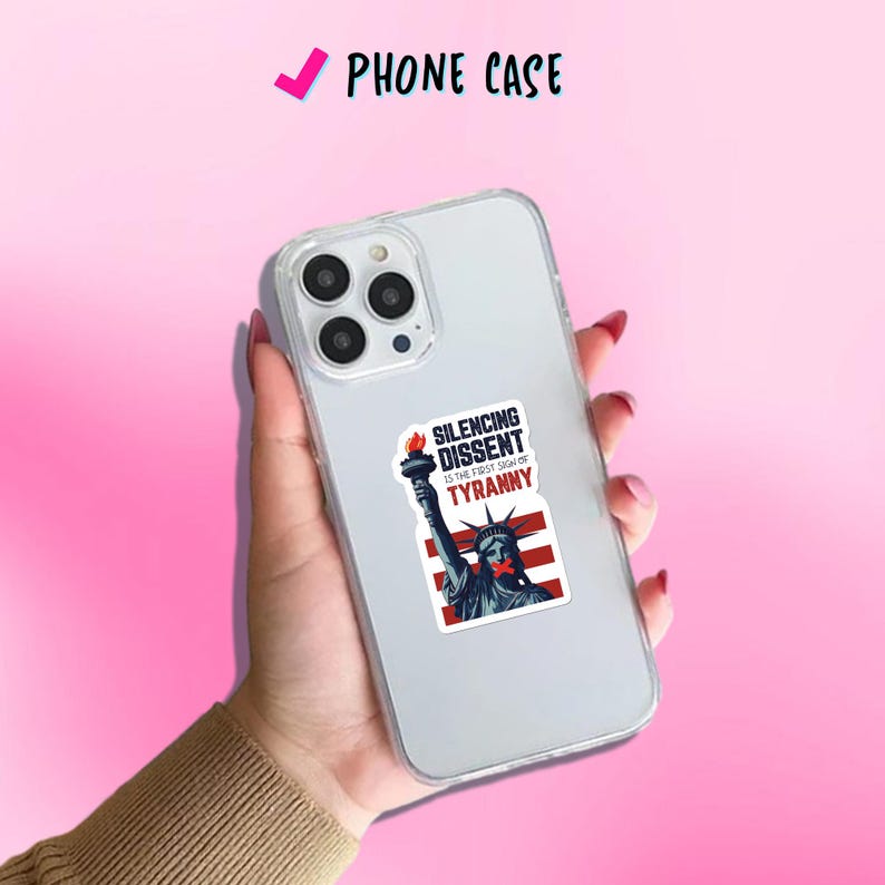 May include: Clear phone case with a sticker featuring the Statue of Liberty with a red band over her mouth and the text "SILENCING DISSENT IS THE FIRST SIGN OF TYRANNY". The phone case is labeled "PHONE CASE".