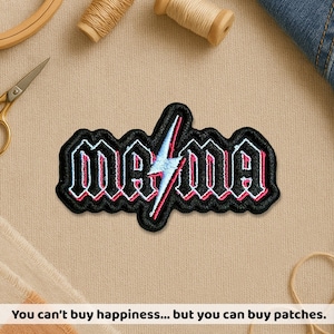 May include: Embroidered patch with the word "Mama" in a gothic font, outlined in black with red and white accents, and a lightning bolt graphic. The patch is on a beige surface with sewing supplies.