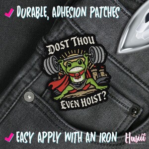 Puede incluir: Parche bordado con una rana de dibujos animados levantando pesas, con el texto "DOST THOU EVEN HOIST?". El parche es negro, verde, rojo y gris, sobre unos vaqueros grises. Tambi&eacute;n se ve el texto "DURABLE, ADHESION PATCHES" y "EASY APPLY WITH AN IRON".