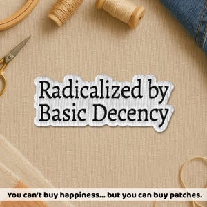 Peut inclure: Un écusson brodé blanc avec le texte "Radicalized by Basic Decency" en noir. L'écusson est rectangulaire avec une bordure légèrement irrégulière. Le fond comprend des fournitures de couture et le texte "You can't buy happiness... but you can buy patches."