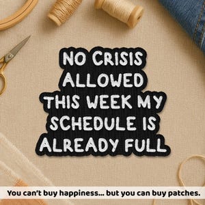 May include: A black patch with white embroidered text: "NO CRISIS ALLOWED THIS WEEK MY SCHEDULE IS ALREADY FULL." Sewing supplies, including scissors, thread spools, and an embroidery hoop, surround the patch. The text at the bottom reads: "You can't buy happiness... but you can buy patches."