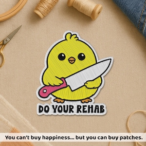 May include: Embroidered patch featuring a yellow chick holding a knife with a pink handle. The chick has black eyes and a small orange beak. The text "DO YOUR REHAB" is below the chick. The patch is on a beige background.