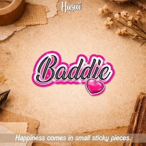 May include: A pink sticker with the word "Baddie" in a black, cursive font, outlined in white. A pink heart is next to the word. The text "Happiness comes in small sticky pieces" is at the bottom.