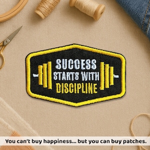 May include: Embroidered patch in black and yellow, featuring the phrase "SUCCESS STARTS WITH DISCIPLINE" and a barbell graphic. The patch has a black background with yellow border and lettering. A fitness-themed item.