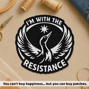 May include: Circular black and white embroidered patch featuring the text "I'M WITH THE RESISTANCE" and a bird design. The patch has a black background and white details. The text "You can't buy happiness... but you can buy patches" is at the bottom.