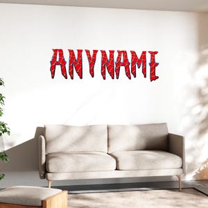 Peut inclure: Décor mural "ANYNAME" rouge et bleu. Les lettres sont dans une police audacieuse et stylisée avec un motif en forme de toile d'araignée. L'œuvre est fixée sur un mur blanc au-dessus d'un canapé beige. La pièce a une esthétique moderne et minimaliste.