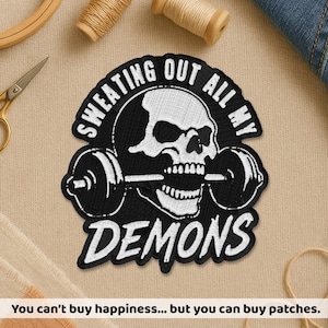 Peut inclure: Écusson brodé noir et blanc représentant un crâne soulevant une barre, avec les mots "SWEATING OUT ALL MY DEMONS" et "DEMONS". Le texte "You can't buy happiness... but you can buy patches" est en bas.