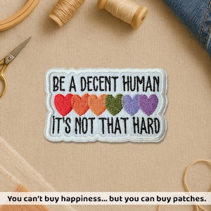 May include: Embroidered patch with the text "BE A DECENT HUMAN IT'S NOT THAT HARD" and five colorful hearts. The patch is white with a stitched border. The hearts are red, orange, green, blue, and purple.