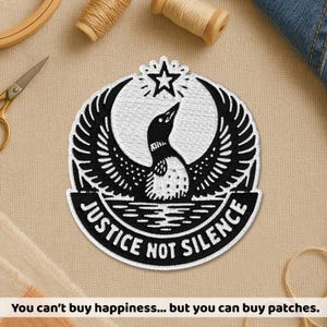 May include: Embroidered patch featuring a black and white loon with outstretched wings, a star, and the text "JUSTICE NOT SILENCE." The patch is circular with a white border. The text at the bottom reads: "You can't buy happiness... but you can buy patches."