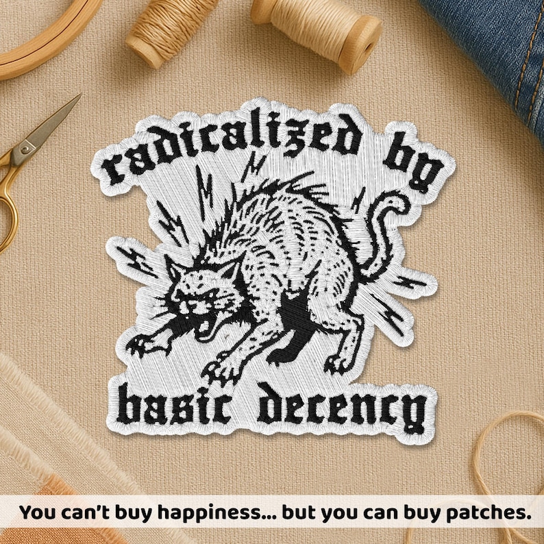 Peut inclure: &Eacute;cusson brod&eacute; blanc avec le texte "radicalized by basic decency" et une illustration en noir et blanc d'un chat en col&egrave;re. L'image comprend &eacute;galement le texte "You can't buy happiness... but you can buy patches."
