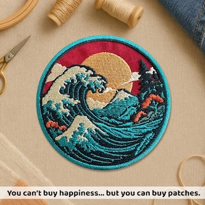 May include: Circular embroidered patch depicting a wave, sun, and mountain scene. The patch has a red backdrop and a blue border. The text "You can't buy happiness... but you can buy patches" is at the bottom. The patch is a decorative item.