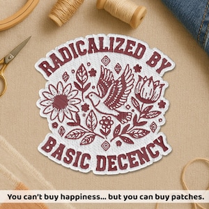 May include: Embroidered patch with the text "RADICALIZED BY BASIC DECENCY" in burgundy. The patch features a dove, flowers, and leaves in a detailed design. The patch is white with burgundy embroidery.