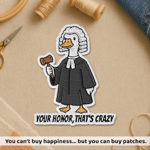 May include: Embroidered patch featuring a goose dressed as a judge, holding a gavel. The goose wears a black robe and a white wig. Text on the patch reads "YOUR HONOR, THAT'S CRAZY". The patch is on a beige fabric background.