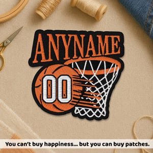 May include: Embroidered patch featuring a basketball design with the text "ANYNAME" in orange on a black background. The patch includes a basketball with the number "00" and a white net. The patch is on a tan fabric.