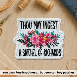 May include: Embroidered patch with the text "THOU MAY INGEST A SATCHEL OF RICHARDS" in black on a white background. The patch features a floral design with pink and yellow flowers and green leaves. The patch is surrounded by a white border.