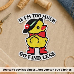 May include: Embroidered patch featuring a yellow duck wearing a black hat with a red flower, a red bow tie, and red boots. The patch has the text "IF I'M TOO MUCH GO FIND LESS". The patch is on a tan fabric background.
