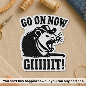May include: Embroidered patch featuring a black and white opossum wearing a cowboy hat and yelling. The text "GO ON NOW GIIIIIIT!" is above and below the opossum. The bottom of the image reads "You can't buy happiness... but you can buy patches."