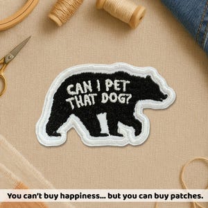 May include: Embroidered patch in the shape of a bear, with the text "CAN I PET THAT DOG?" in white on a black bear. The patch has a white border. A fun accessory for jackets, bags, or other fabric items.