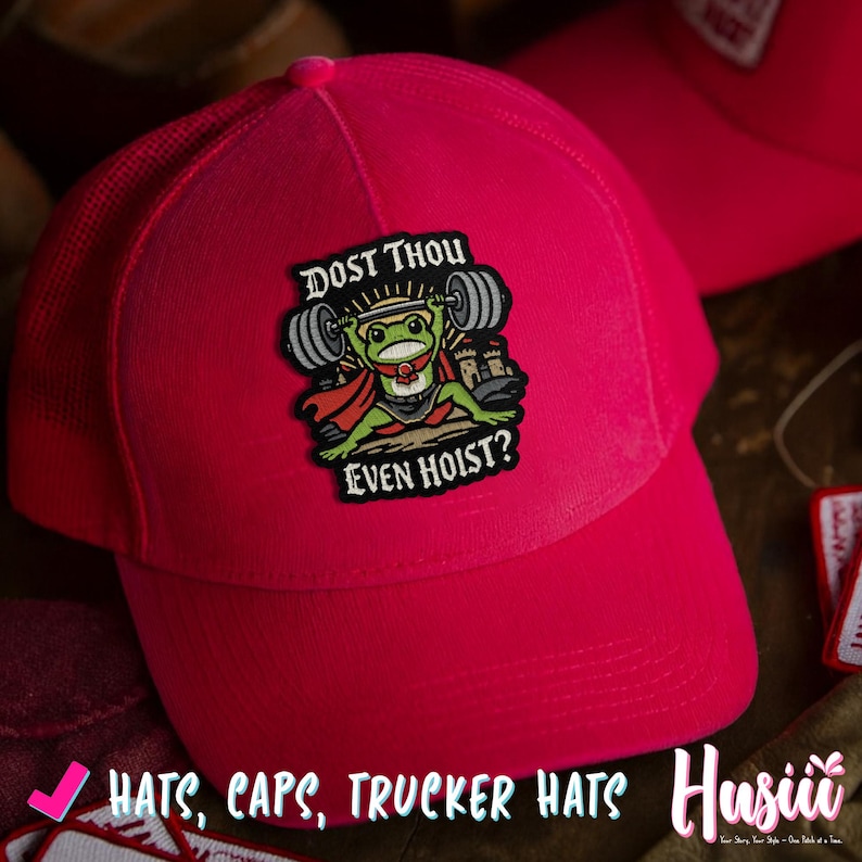 Puede incluir: Gorra de camionero rosa brillante con la parte trasera de malla. La parte delantera presenta un parche con una rana de dibujos animados levantando pesas, el texto dice "DOST THOU EVEN HOIST?" y las palabras "HATS, CAPS, TRUCKER HATS" est&aacute;n en la parte inferior.