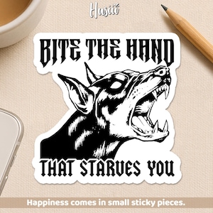 May include: A black and white sticker featuring a snarling dog with the text "BITE THE HAND THAT STARVES YOU." The sticker has a white border and includes the text "Happiness comes in small sticky pieces."