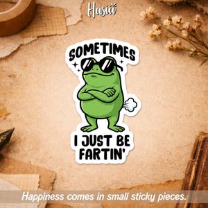 May include: A green frog sticker wearing sunglasses with the text "SOMETIMES I JUST BE FARTIN'". The sticker has a white border and a cartoon style. The sticker is on a tan background with the text "Happiness comes in small sticky pieces."