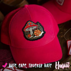Pu&ograve; includere: Cappellino da camionista rosa acceso con retro in rete e visiera curva. Il cappello presenta una toppa ricamata con un design a fungo, lumaca e foglie. Il testo "HATS, CAPS, TRUCKER HATS" &egrave; visibile nell'immagine.