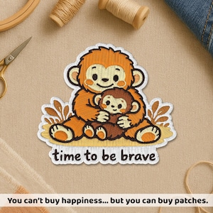 May include: Embroidered patch showing a mother monkey embracing a baby monkey, in orange and brown hues. The patch reads "time to be brave" in white. The patch is set against a beige backdrop.