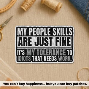 May include: Embroidered patch with the text "MY PEOPLE SKILLS ARE JUST FINE. IT'S MY TOLERANCE TO IDIOTS THAT NEEDS WORK." in black and white. The patch is rectangular with a black border. The background includes sewing supplies.