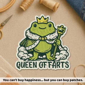 May include: Embroidered patch of a green frog wearing a crown and holding a scepter. The patch reads "QUEEN OF FARTS" in white text. The image also includes the text "You can't buy happiness... but you can buy patches."