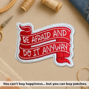 May include: Embroidered patch with the text "BE AFRAID AND DO IT ANYWAY" in white on a red banner with a white border. The patch is surrounded by sewing supplies.