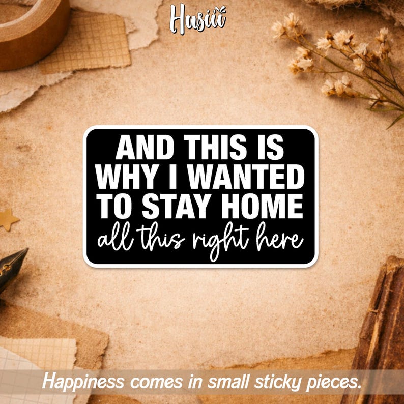 May include: A black sticker with white text that reads "AND THIS IS WHY I WANTED TO STAY HOME all this right here." The sticker is rectangular with rounded corners. The background is a textured, tan surface.