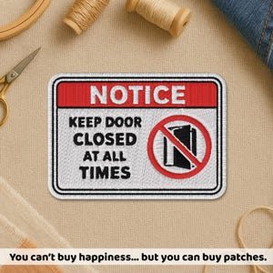 May include: Embroidered patch with a red and white border, featuring the word "NOTICE" at the top. Below, it reads "KEEP DOOR CLOSED AT ALL TIMES" with a crossed-out door symbol. The patch is rectangular and has a black and white design.