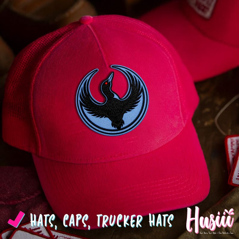 K&ouml;nnte beinhalten: Leuchtend pinkfarbene Trucker-Cap mit einem schwarzen Vogel-Emblem auf hellblauem Hintergrund. Der Vogel hat rote Augen und ist von einem hellblauen Ring umgeben. Die Cap hat einen Mesh-R&uuml;cken und einen gebogenen Schirm. Der Text auf dem Bild lautet "HATS, CAPS, TRUCKER HATS".