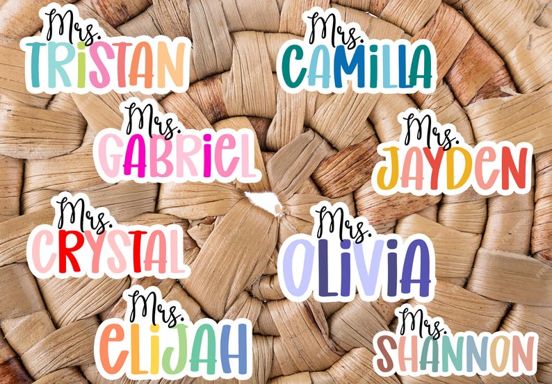 K&ouml;nnte beinhalten: Neun bunte Lehrer-Namensschilder mit dem Titel "Frau" gefolgt von einem Namen. Die Namen sind Tristan, Camilla, Gabriel, Jayden, Crystal, Olivia, Elijah und Shannon.