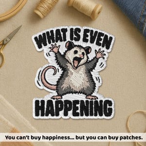 May include: An embroidered patch featuring a gray and white opossum with its mouth open and arms raised in a startled pose. The black text above the opossum reads WHAT IS EVEN and the black text below the opossum reads HAPPENING.