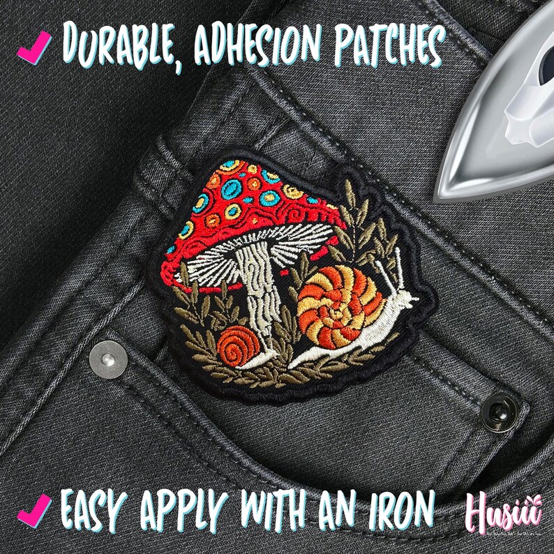 Pu&ograve; includere: Toppa ricamata con un fungo rosso, uno stelo bianco e un motivo a chiocciola. Il testo recita "Durable, Adhesion Patches" e "Easy Apply With An Iron". La toppa &egrave; su un paio di jeans grigio scuro.