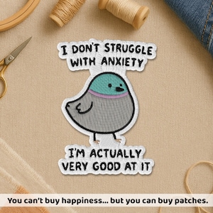May include: Embroidered patch featuring a cartoon bird with the text "I DON'T STRUGGLE WITH ANXIETY I'M ACTUALLY VERY GOOD AT IT." The bird has a teal head, gray body, and a pink collar. The patch is white with black text.